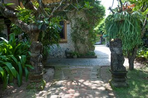 Un chemin de pierres mène à une maison traditionnelle dotée d’une fenêtre et d’un mur en pierre.