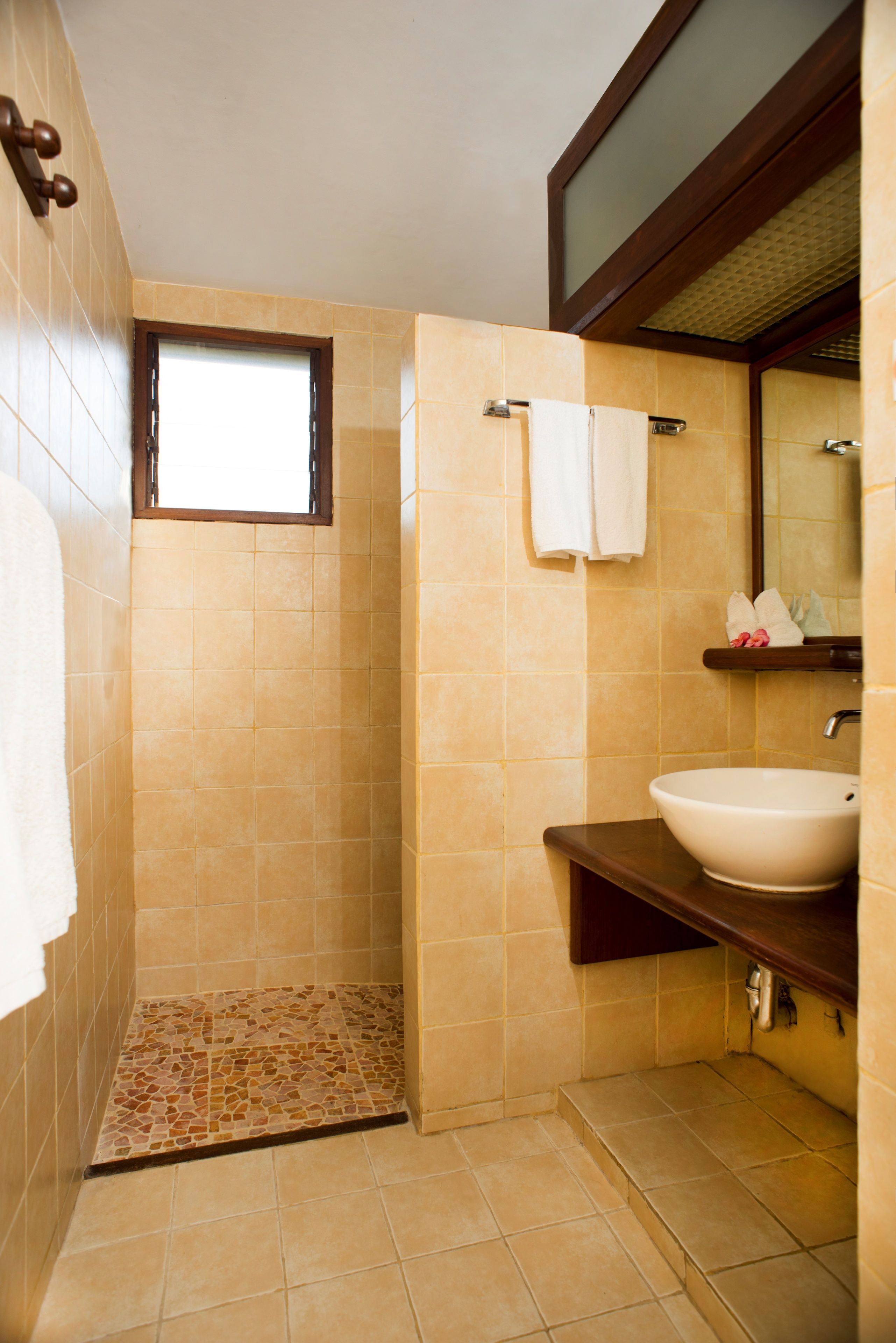 Ein Badezimmer mit Dusche, Waschbecken, Spiegel und Fenster.