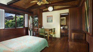 Une pièce comprenant un lit, un plafond en bois, une table à manger avec des chaises, un ventilateur de plafond et une vue sur la verdure à l’extérieur.