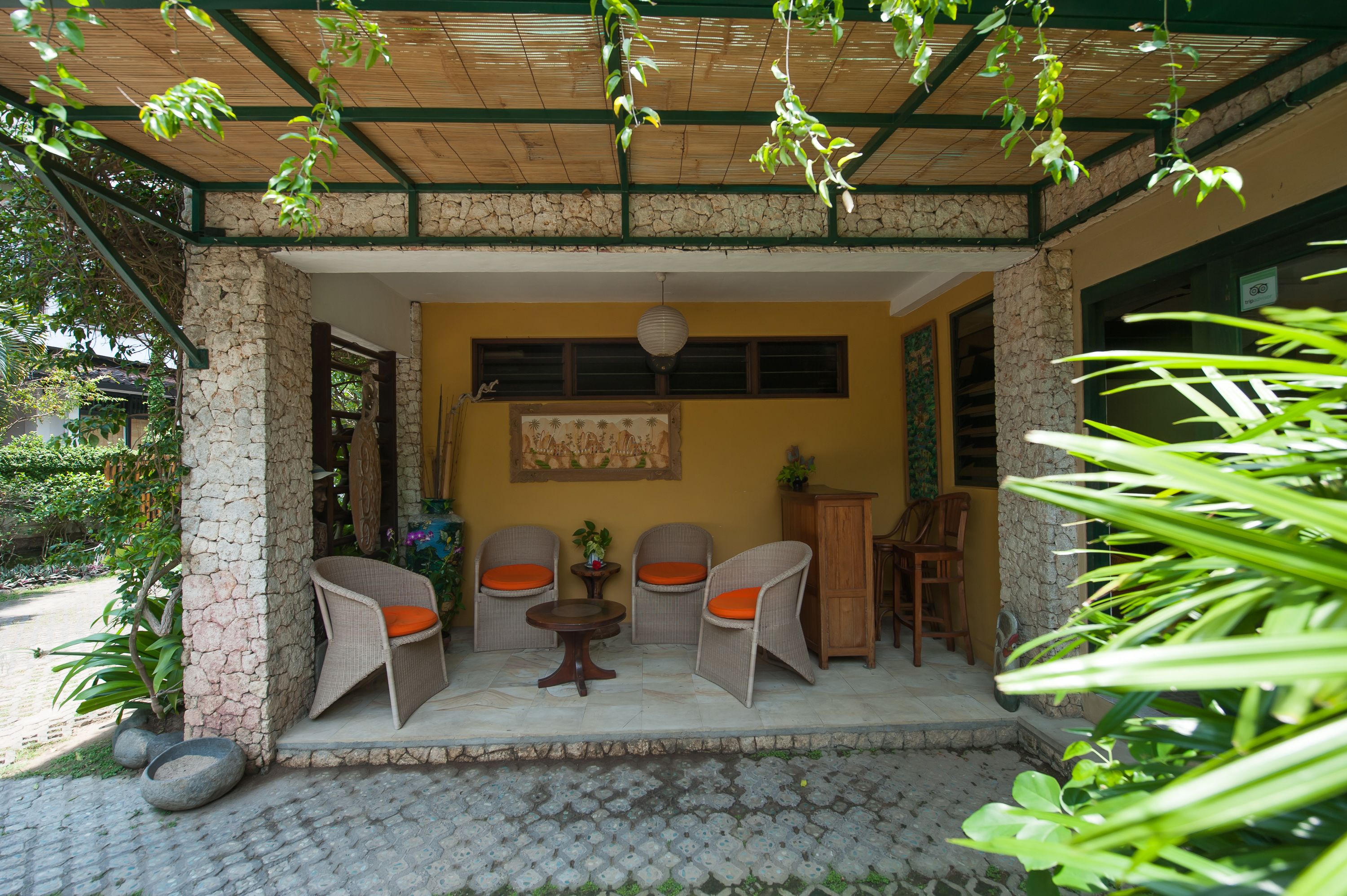 An outdoor patio with wicker chairs and a table, stone pillars, and a stone wall.