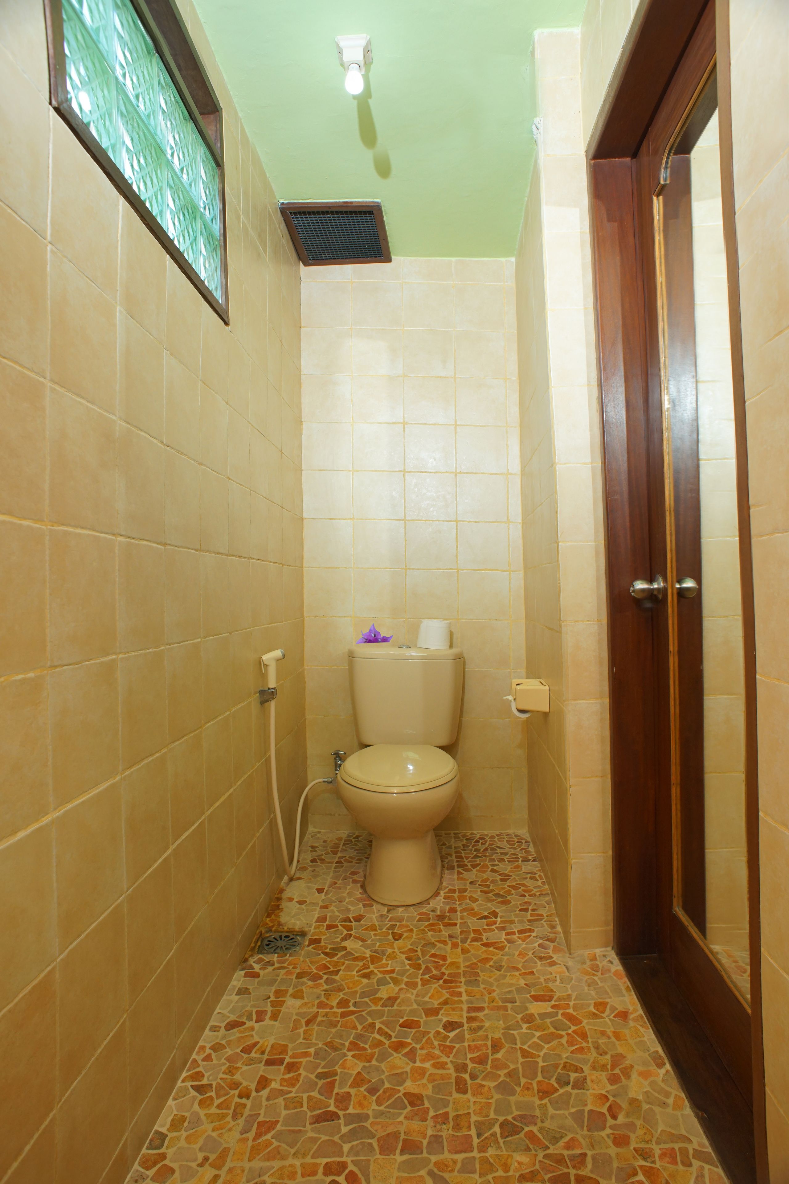 A small bathroom with a toilet, a shower, and a tiled floor.