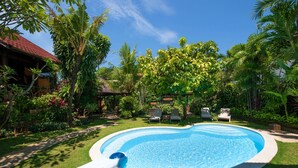 Une piscine entourée d’une végétation luxuriante et agrémentée d’une structure en bois.