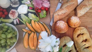 Verschiedene Speisen wie Trauben, Melonenstücke, Käse und Brot auf einem Holztisch.