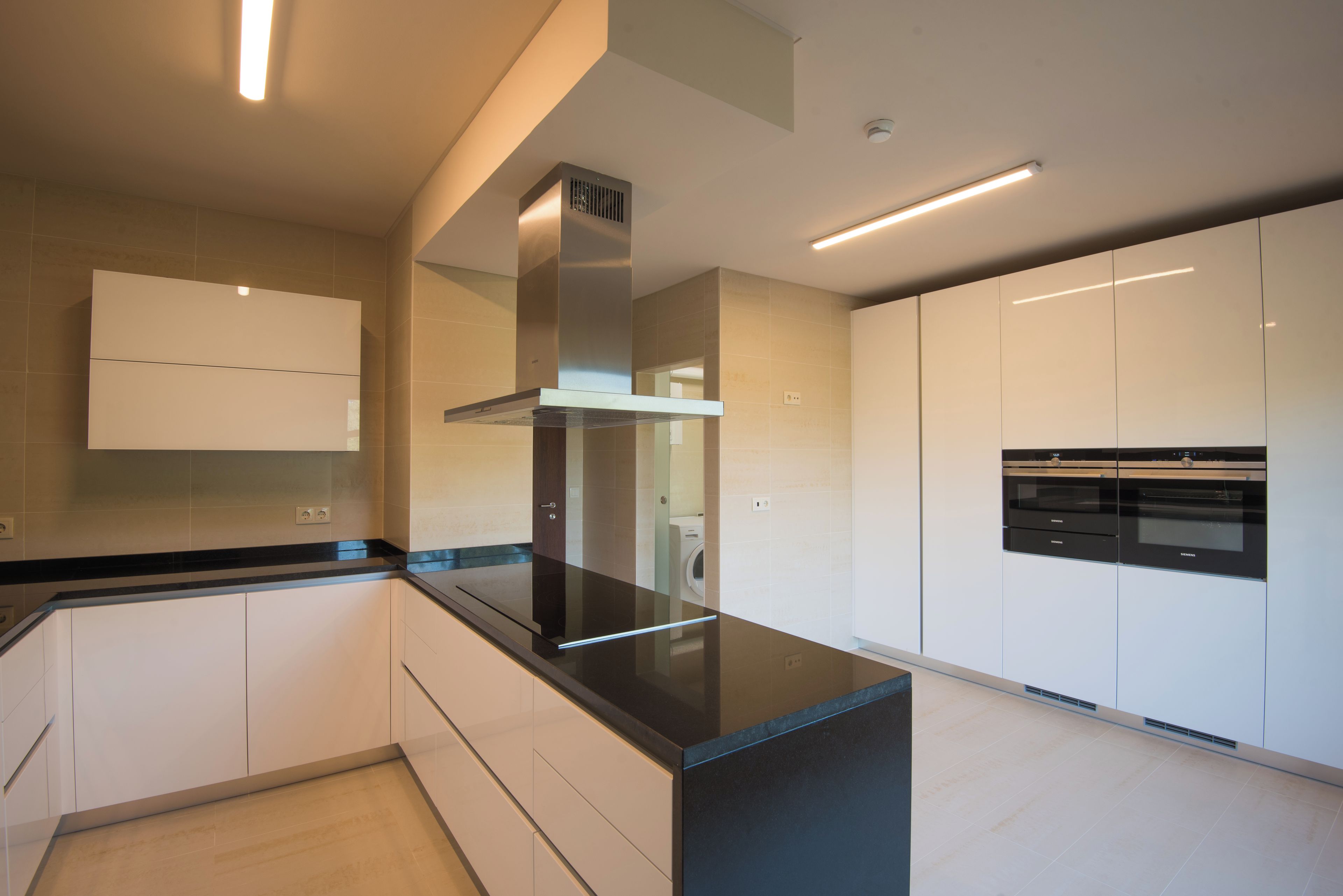 A modern kitchen with white cabinetry, a black countertop, and built-in appliances.