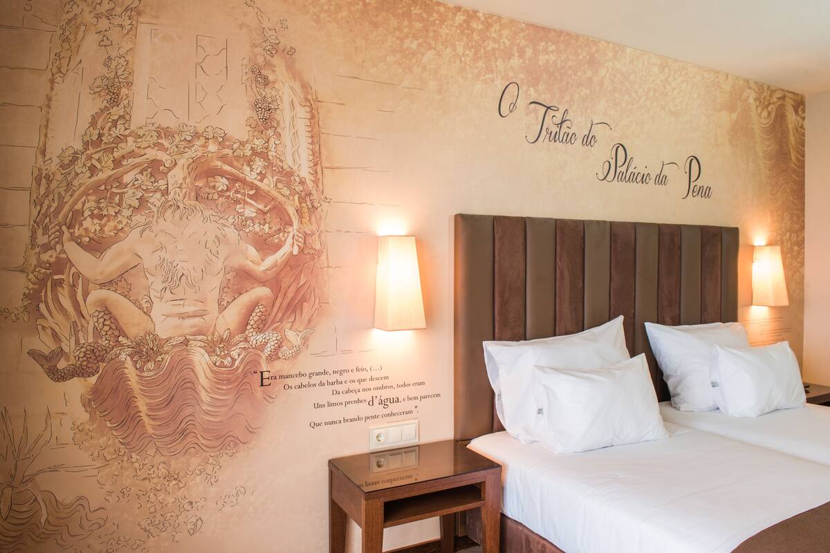 Ein Hotelzimmer mit einer großen Wandmalerei, einem Bett mit weißer Bettwäsche und zwei Nachttischlampen.