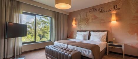 Une chambre d’hôtel dotée d’un grand lit, d’un téléviseur à écran plat, d’une fenêtre avec des rideaux, d’une lampe fixée au mur et d’un élément décoratif mural.