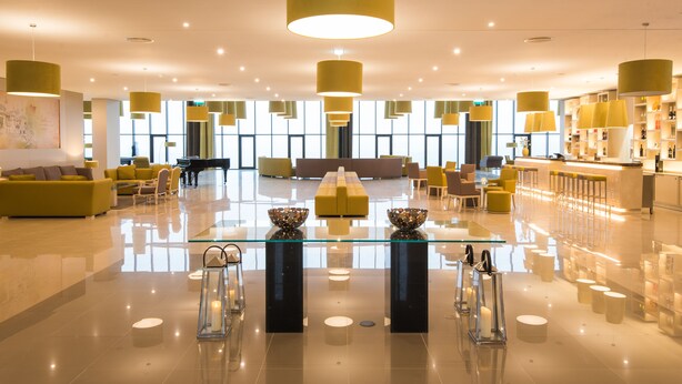 A spacious lobby with a central seating area, a piano, and a bar.