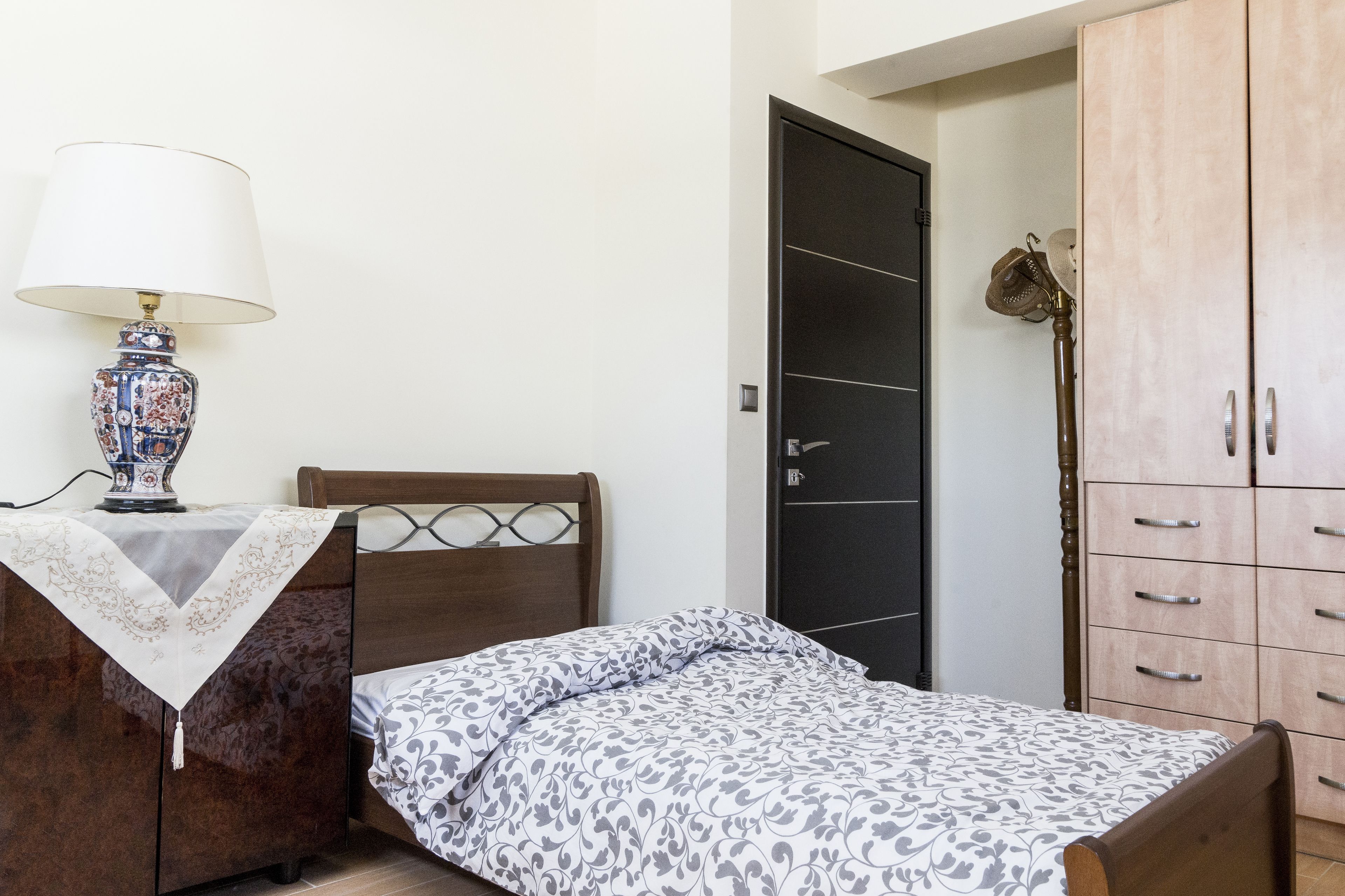 Une chambre à coucher avec un lit, une table de chevet avec une lampe, une armoire et une porte.