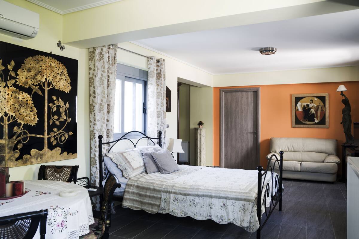 A bedroom with a bed, a chair, a table, and a painting on the wall.