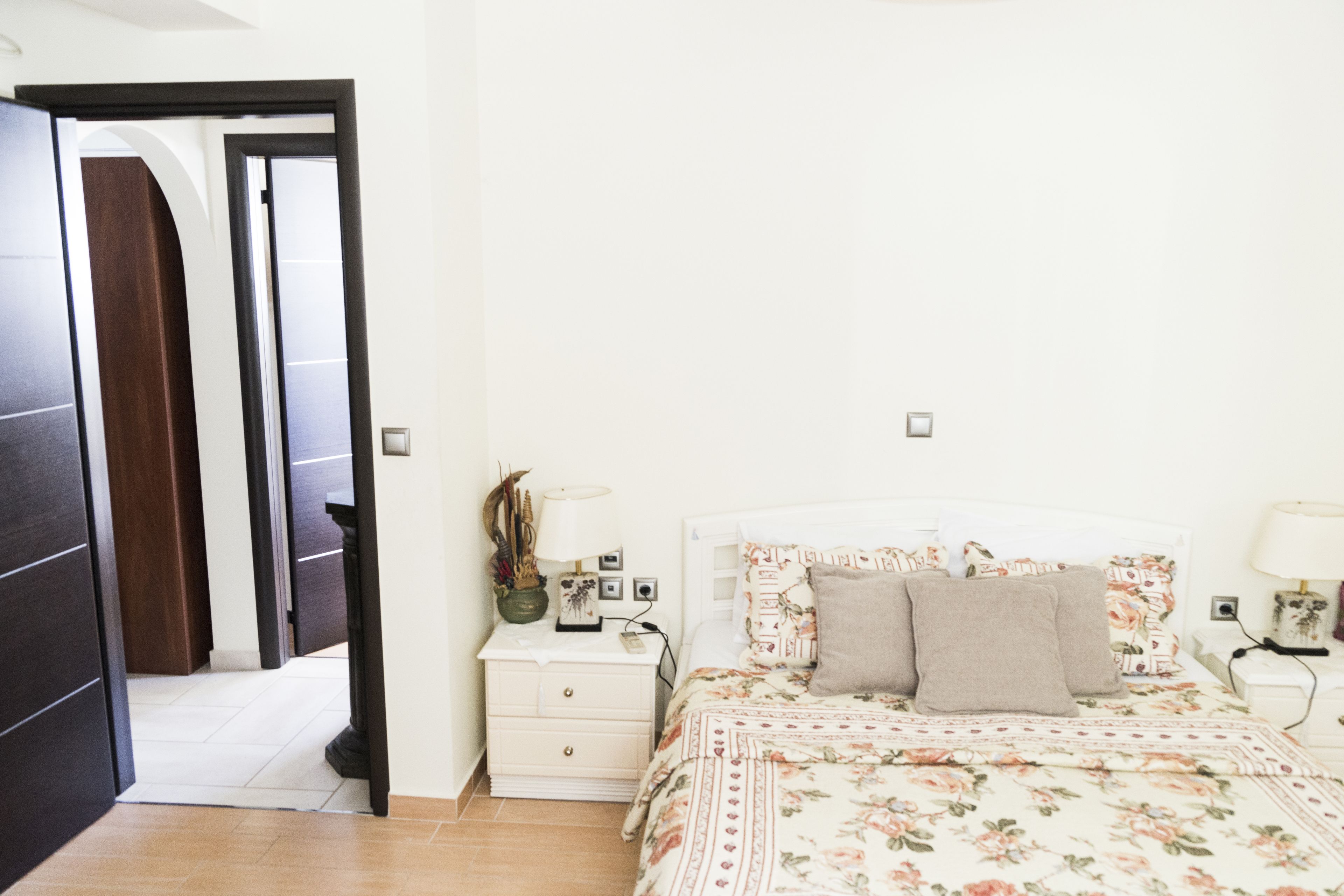 A bedroom with a bed, nightstands, a dresser, and a door.