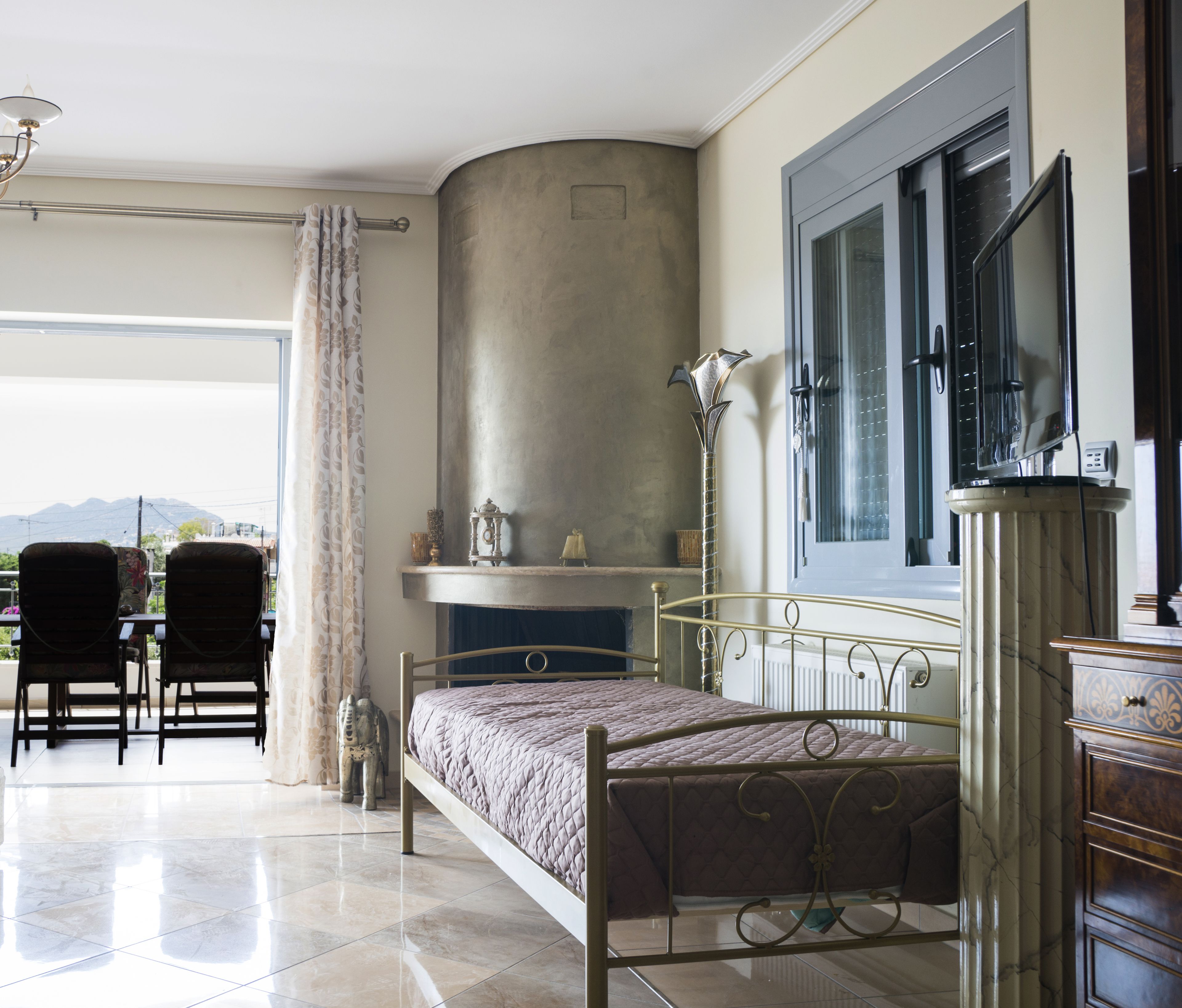 A bedroom with a bed, a fireplace, a window, and a view of the outdoors.
