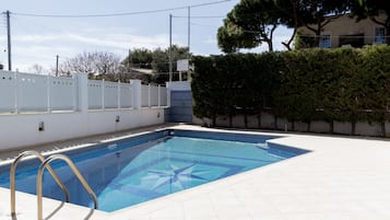 Una piscina al aire libre, sillones reclinables de piscina