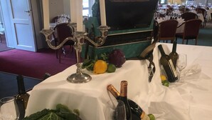 Una mesa dispuesta para una comida, con una botella de vino, una copa y un ramo de verduras.