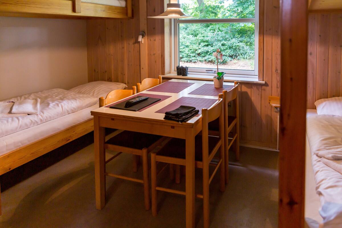 A compact room with a wooden table and two single beds.