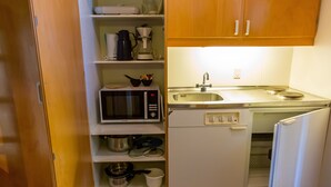 Una cocina compacta con microondas, cafetera y lavabo.