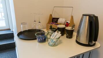 A kitchenette with a coffee maker, glass containers, and a box of tissues.