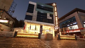 Et moderne hotel med et markant skilt, en veloplyst indgang og et belagt udendørsareal.