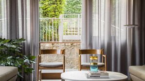 Una habitación con dos sillas de madera, una mesa redonda con un libro y una planta en maceta.