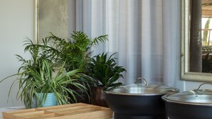 Un bufé de desayuno con diversos alimentos, incluyendo huevos y carnes, sobre una mesa con plantas en macetas y grandes jarrones al fondo.