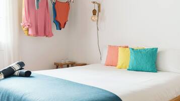 Una cama con una manta azul, un cabecero de madera y almohadas coloridas.