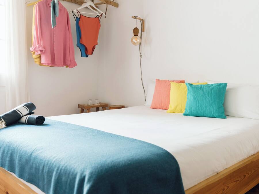 Una cama con una manta azul, un cabecero de madera y almohadas coloridas.