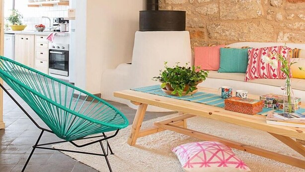 Un salon chaleureux avec un mur en pierre, une cheminée, un hamac et une table basse en bois.