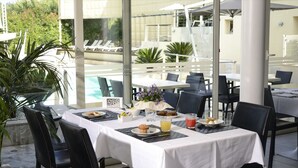 A dining area with tables set for breakfast, overlooking a pool and greenery. - La Villa Resort (Pieve a Nievole)