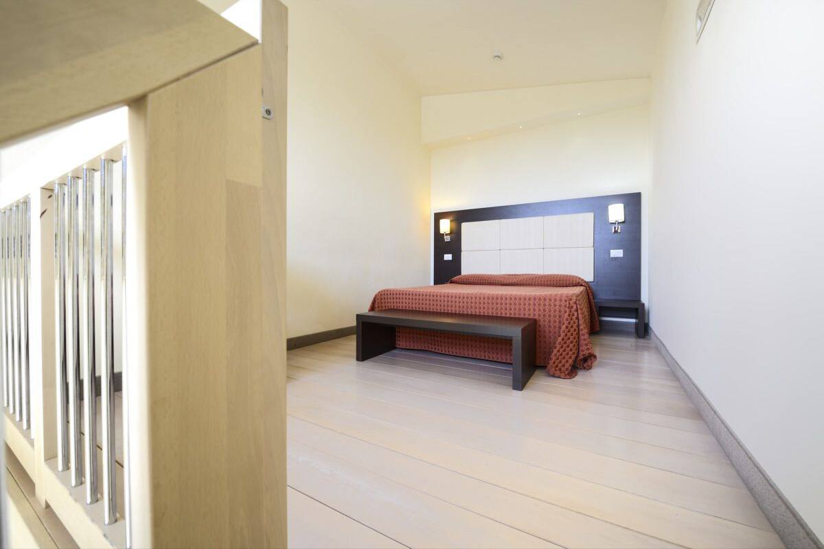 A bedroom with a bed, bedside table, and a headboard with wall-mounted lights.