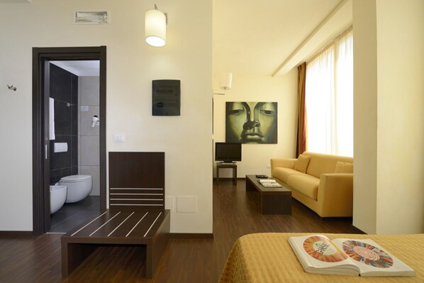 A hotel room with a bed, a bedside table, a sofa, a TV, and a painting on the wall. - La Villa Resort (Pieve a Nievole)