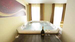 A spa room with a hot tub, a bottle of champagne, and two glasses on a wooden table. - La Villa Resort (Pieve a Nievole)