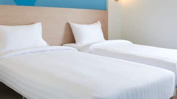 Una habitación de hotel con dos camas, una maleta azul y una pared con un diseño abstracto en tonos azules.