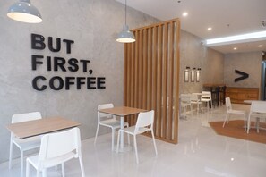 Un café moderno con un separador de madera, sillas y mesas blancas.