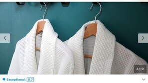 Deux robes blanches sont suspendues à des cintres en bois devant un mur de couleur turquoise.