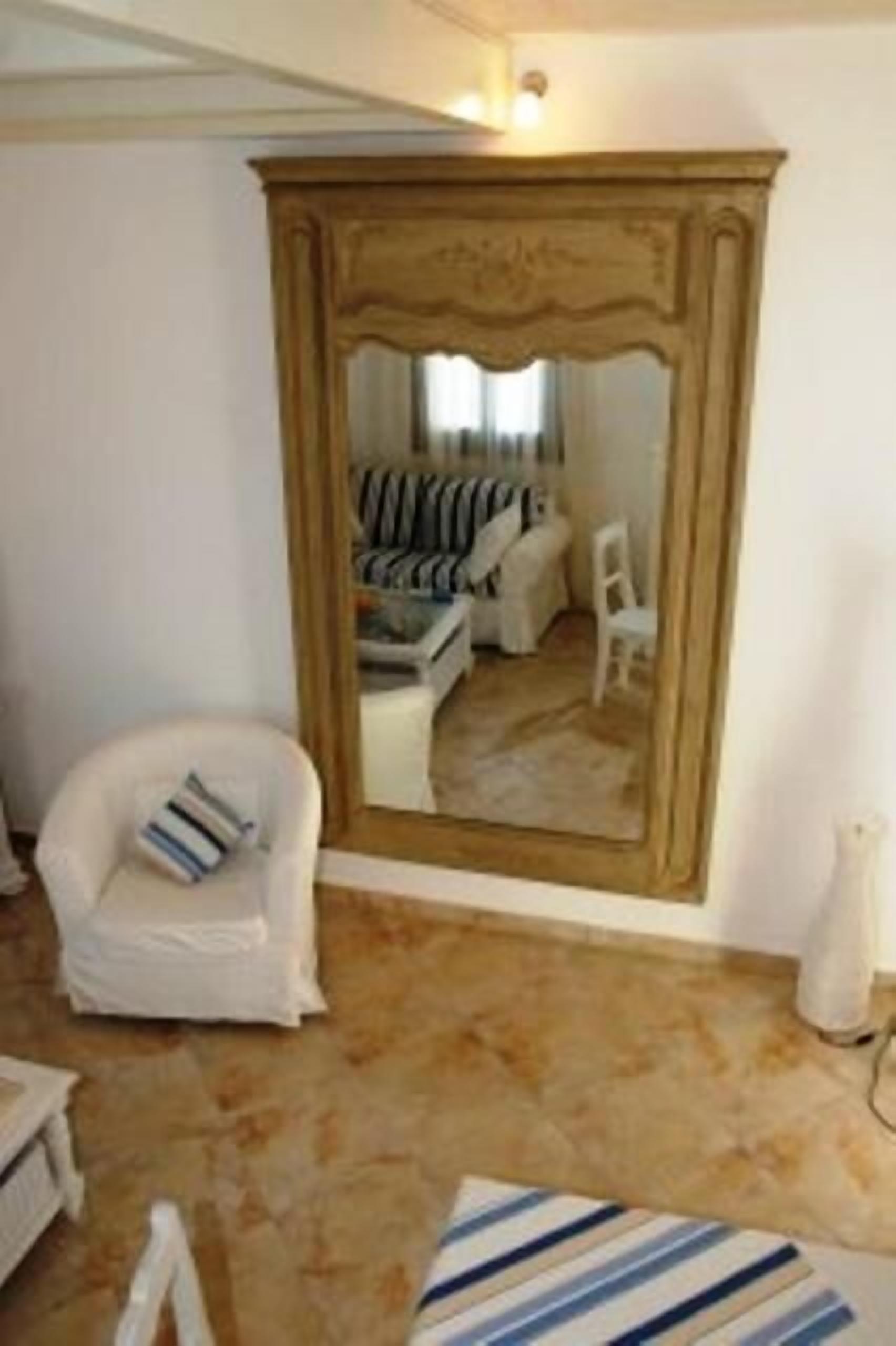 A living room with a large mirror, a white armchair, a striped rug, and a sofa with striped cushions.