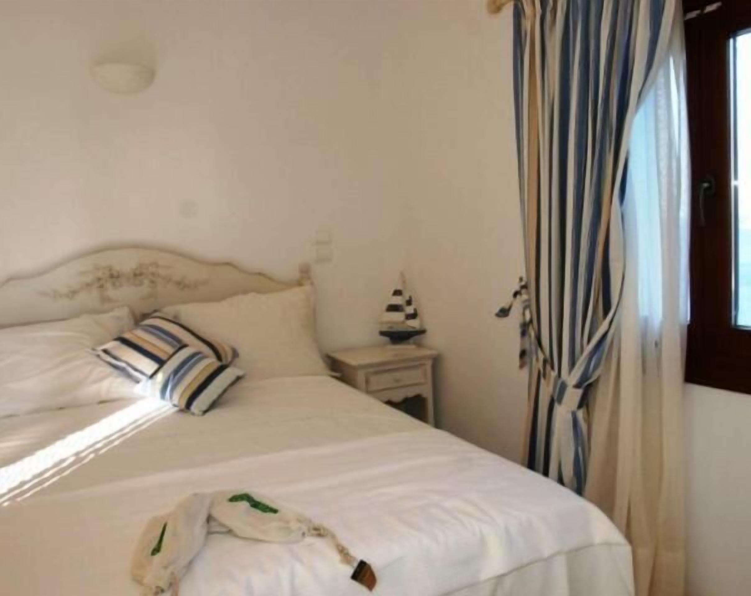A bedroom with a bed, a nightstand, and a window with curtains.