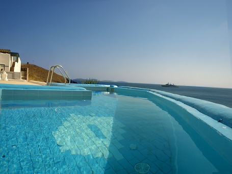 Una piscina al aire libre, sombrillas, sillones reclinables de piscina