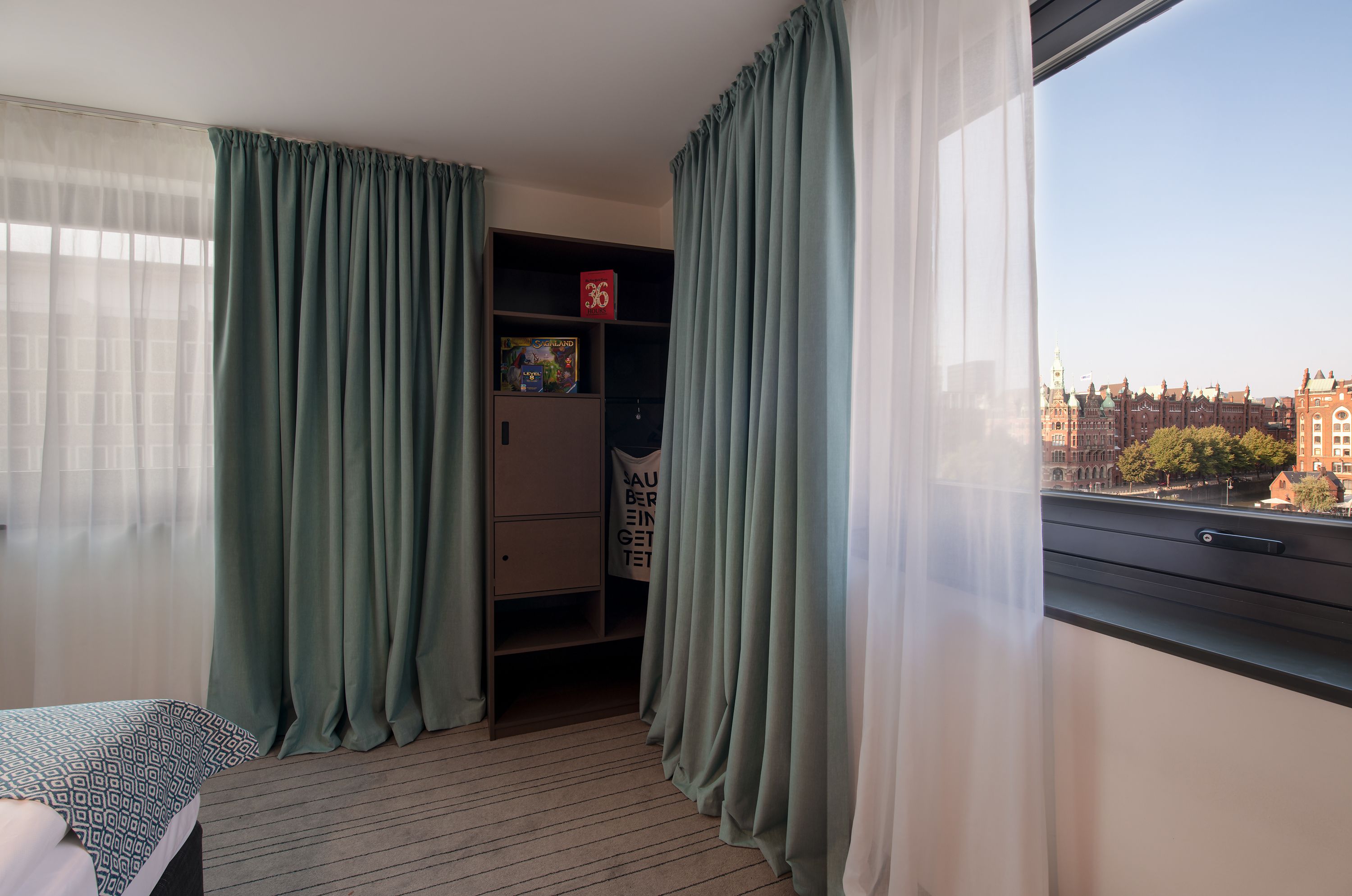 Una habitación con cama, armario y ventana con vista a edificios.