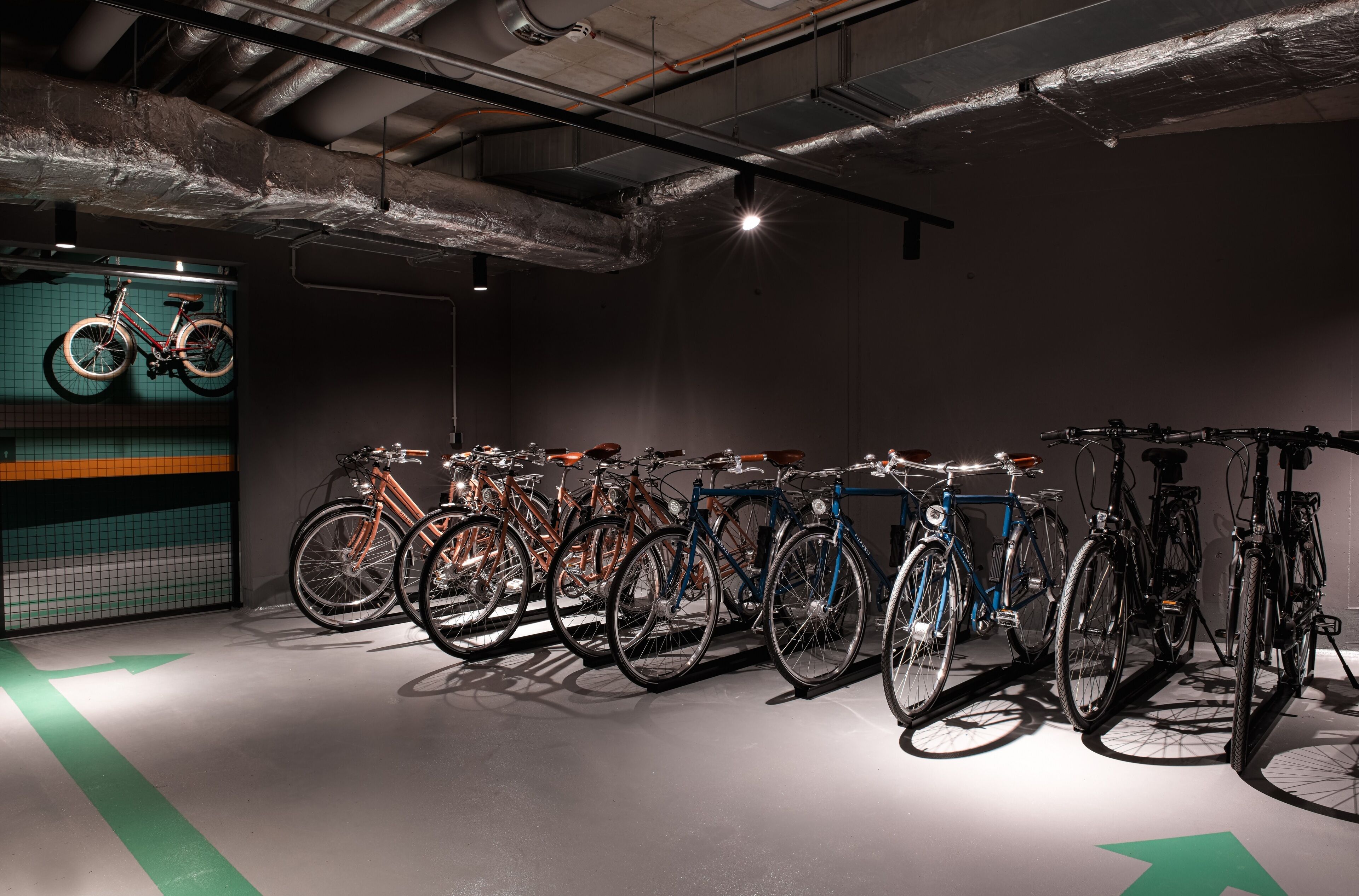 Un área de estacionamiento para bicicletas con varias bicicletas y una flecha direccional verde en el suelo.