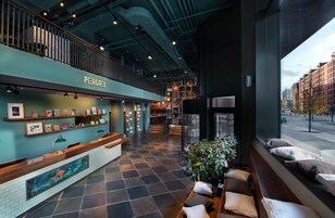 Ein modernes Interieur mit einer Rezeption, Kunstwerken und Blick auf die Stadt durch große Fenster.