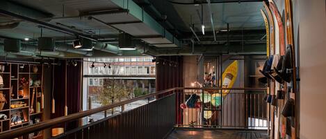 A spacious interior with a high ceiling, exposed ductwork, and a balcony with a railing.