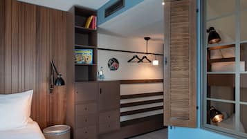 A bedroom with a bed, a wardrobe, a hanging light fixture, and a window with a view.
