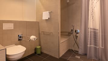 Une salle de bain moderne équipée de toilettes, d’une douche et d’un porte-serviettes.