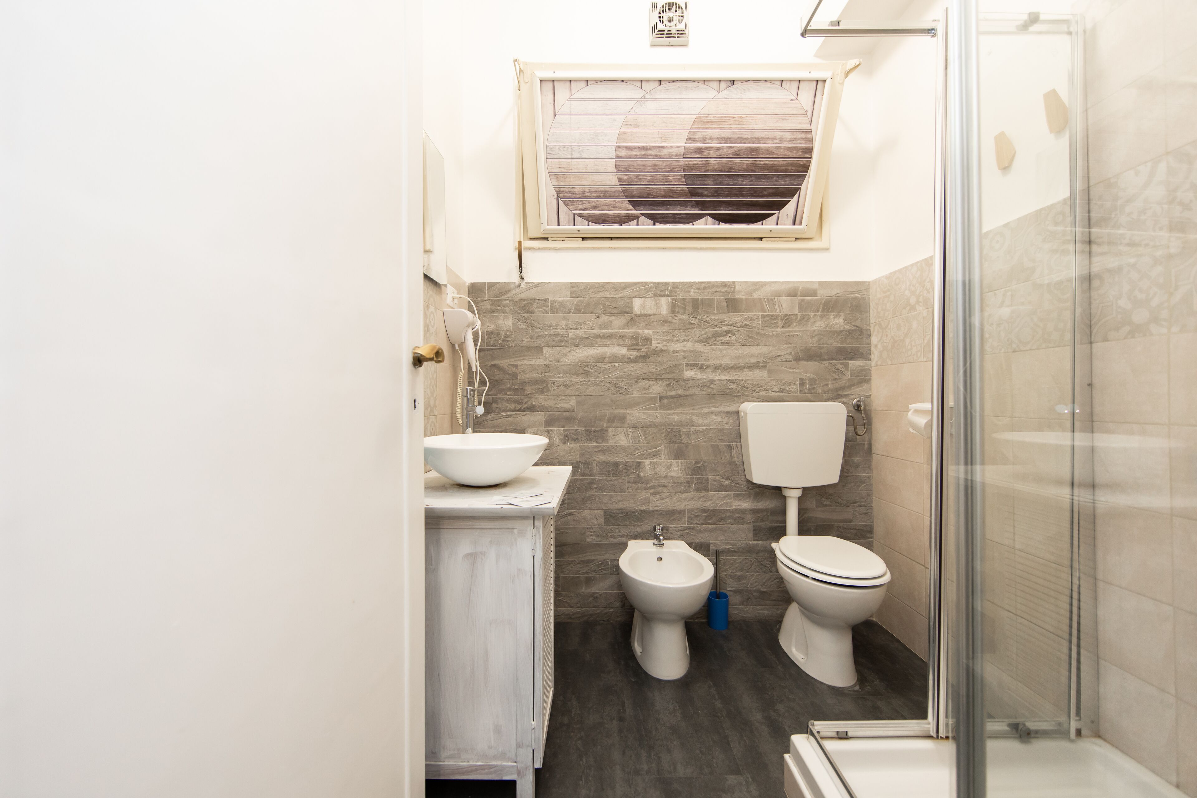 A compact bathroom with a sink, bidet, toilet, and a shower area.