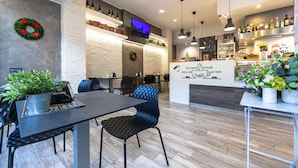 A modern cafe interior with a wooden floor, black and blue chairs, a black table, and a counter with a sign that reads "Cafe D'ornals". - Imperiale Roma Trastevere (Rome)