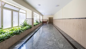 A long, narrow hallway with a marble floor and a planter with green plants on one side. - Imperiale Roma Trastevere (Rome)