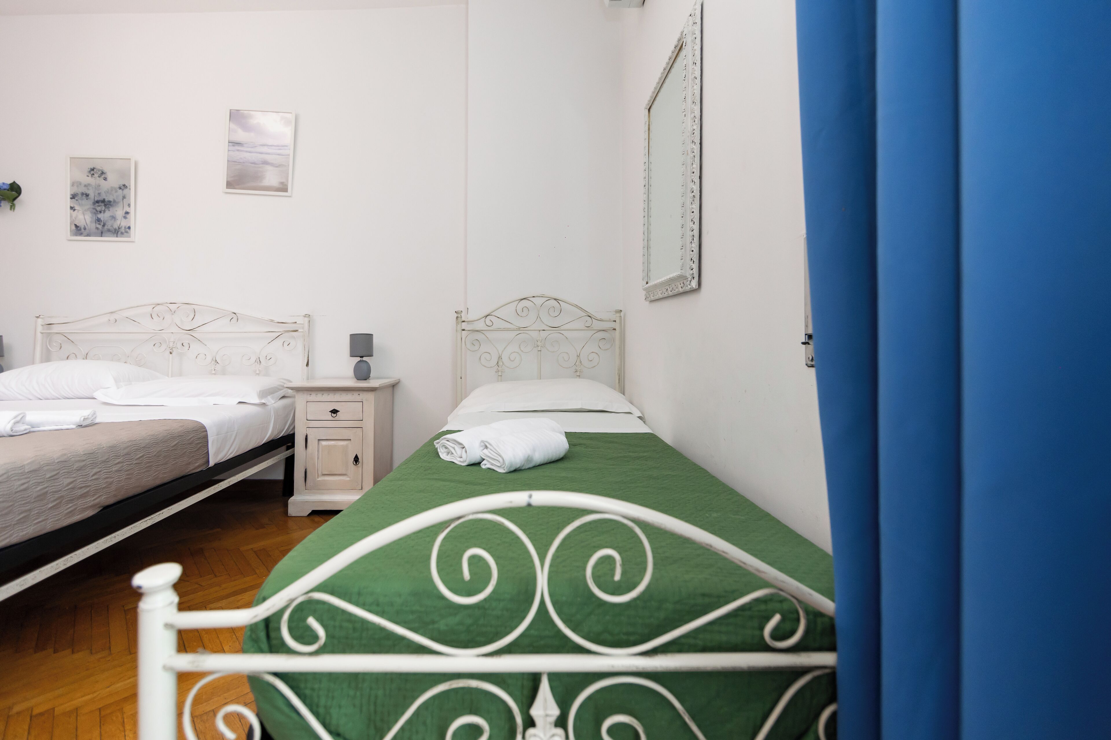 Un dormitorio con dos camas, una mesita de noche y un espejo en la pared.