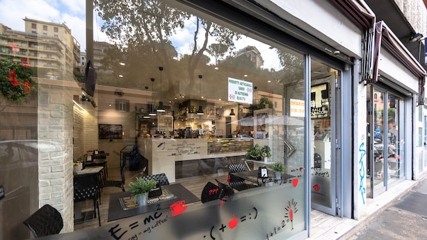 A coffee shop with a glass storefront, interior seating, and a sign advertising artisanal products. - Imperiale Roma Trastevere (Rome)