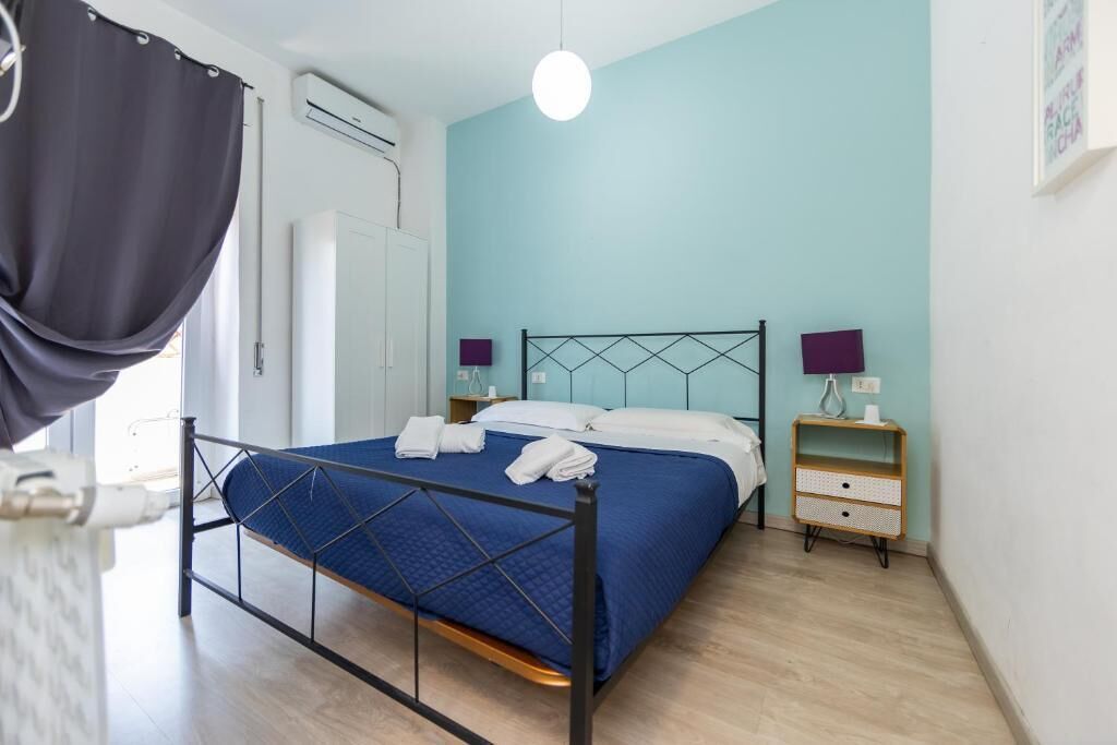 A bedroom with a bed, bedside tables, and a window with curtains.