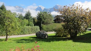 Un jardin luxuriant avec un sentier de pierres, des plantes en fleurs et un chalet en bois.