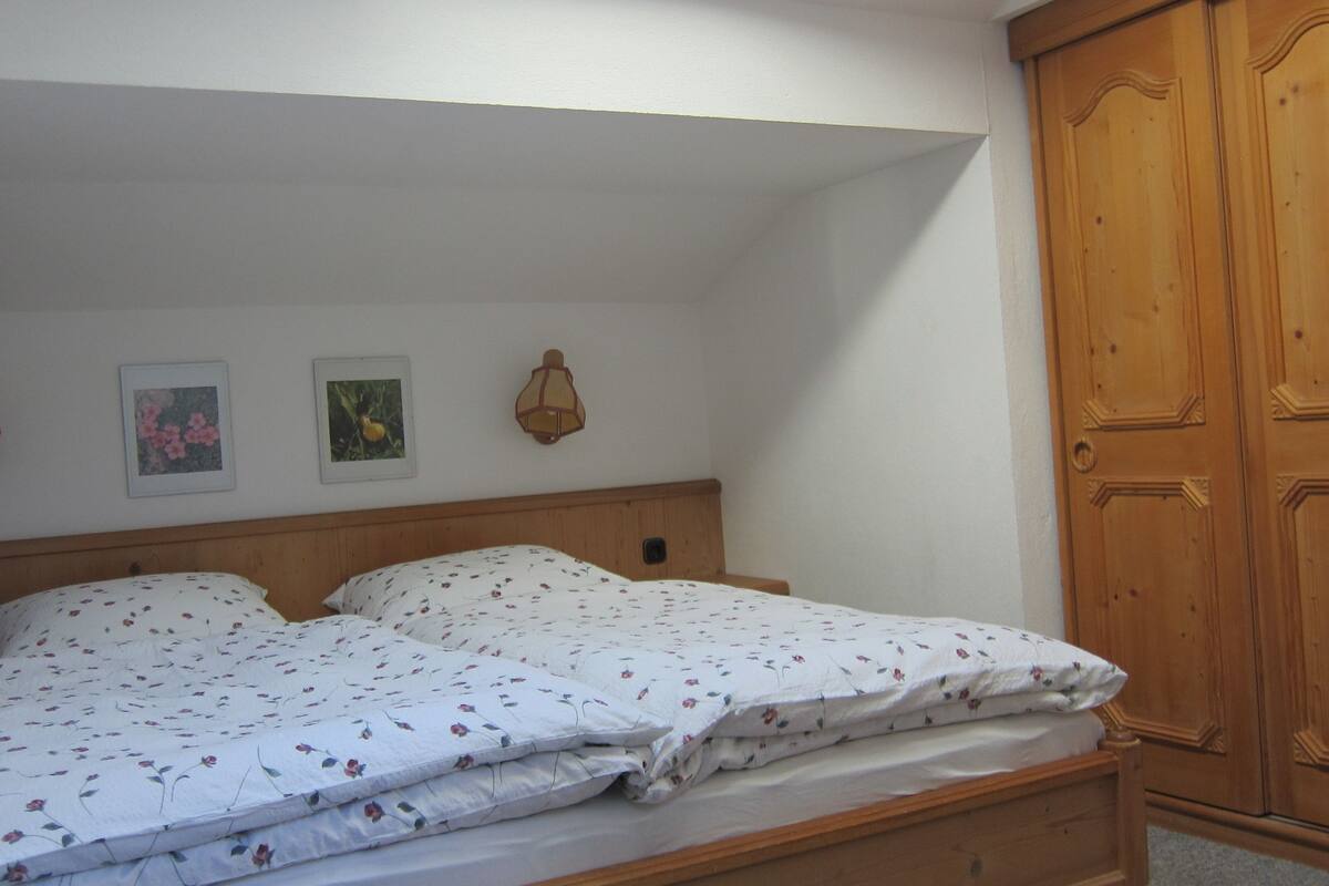 A bedroom with a wooden bed, a wardrobe, and three wall-mounted lamps.